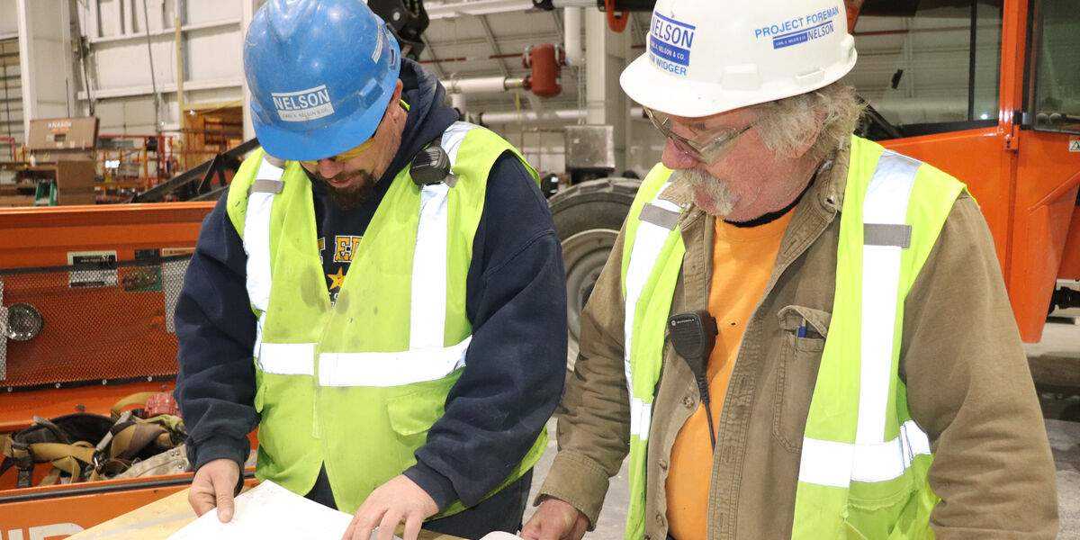 Members of the Design-Build construction crew from Carl A. Nelson & Company review drawings on an industrial construction site in Iowa.